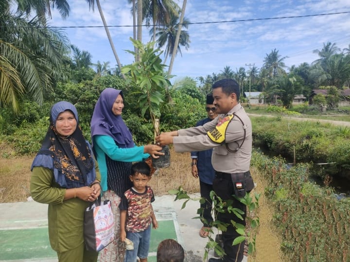 Personel Polsek Bantan Dampingi Pemdes Teluk Lancar Bagikan Bibit Buah kepada Warga