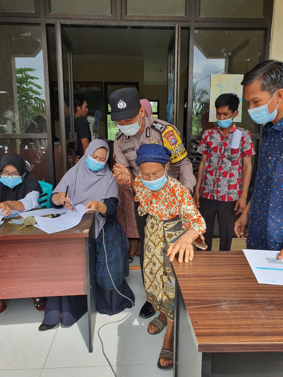 Bhabinkamtibnas Desa Teberau Panjang Bantu Ibu Lansia untuk di Vaksin