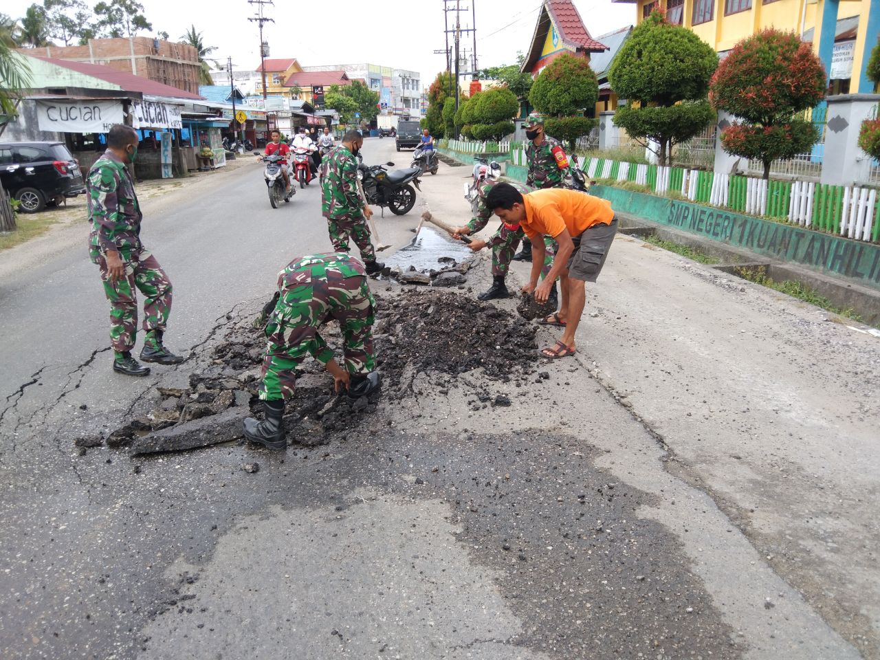 Serma Muhardi Gotong-Royong Memperbaiki Jalan Yang Rusak Bersama Anggota Koramil 07/Kuantan Hilir Lainnya